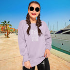 Woman wearing a lavender sweatshirt with text, sunglasses, and braided hair by a marina.