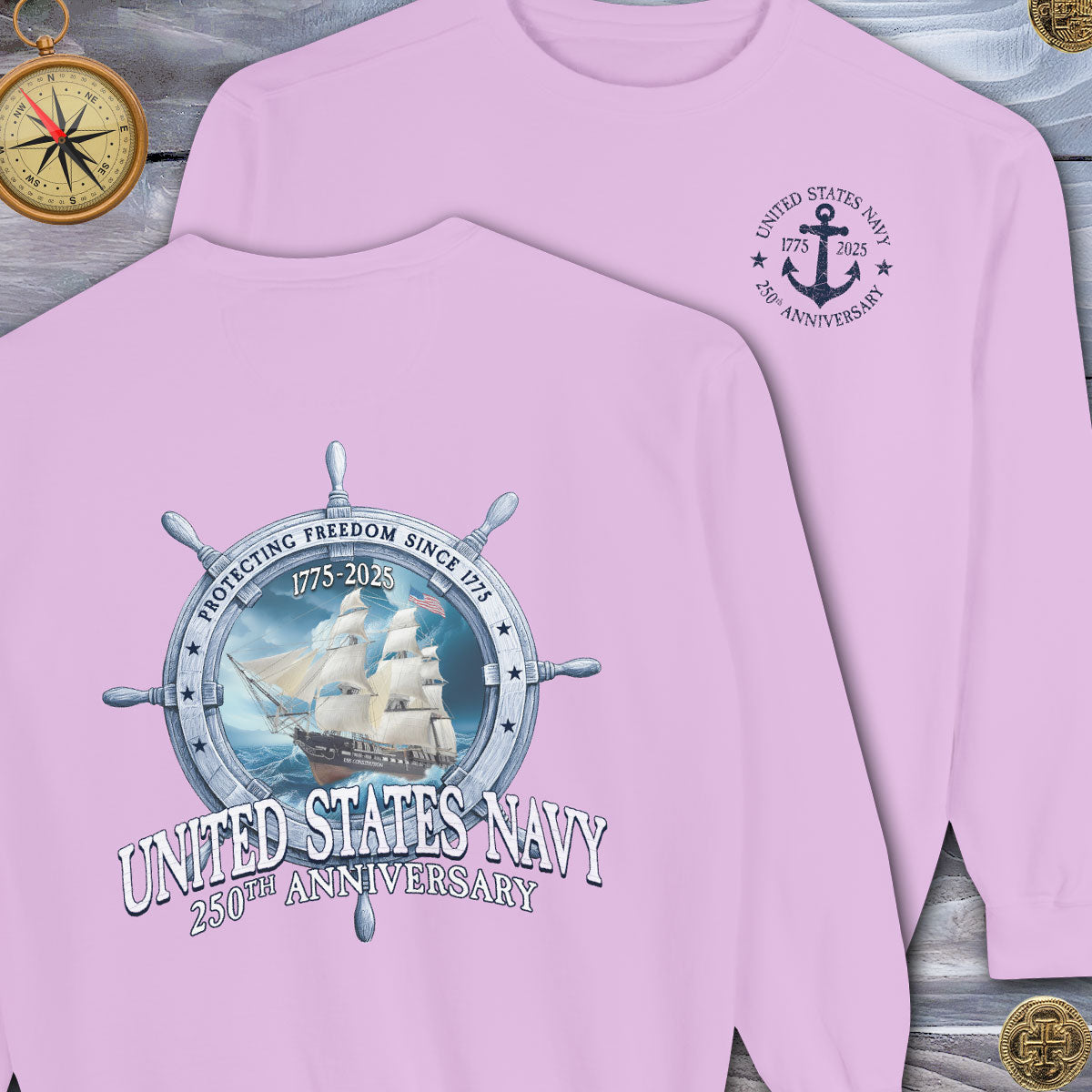 Pink long-sleeve shirt with United States Navy 250th Anniversary design on a wooden surface.