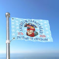 Flag with a parrot design and text celebrating 250 years of freedom against a blue sky.