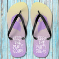 Pair of ParrotHead Flip-Flops with purple soles and black straps on a wooden surface.
