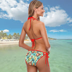 Woman in a colorful bikini with a tropical pattern standing on a beach.