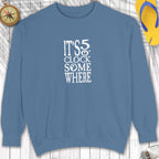 Blue sweatshirt with 'It's 5 o'clock somewhere' text on a wooden surface.