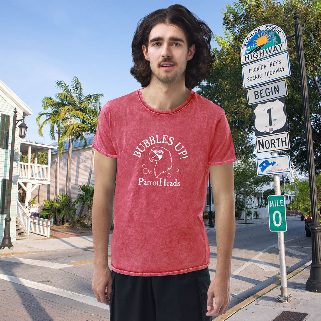 Man wearing a red t-shirt with 'Bubbles Up! ParrotHeads' text standing on a street corner with scenic highway signs.