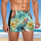 Person wearing tropical-themed swim shorts with parrots and flowers on a beach background