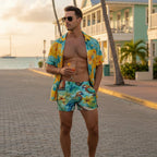 Man in colorful parrothead bathing suit and shirt holding a drink on a beachside street in Key West.