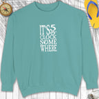 Teal sweatshirt with 'It's 5 o'clock somewhere' text on a wooden surface.