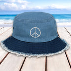 Blue bucket hat with peace symbol on a wooden surface with beach background