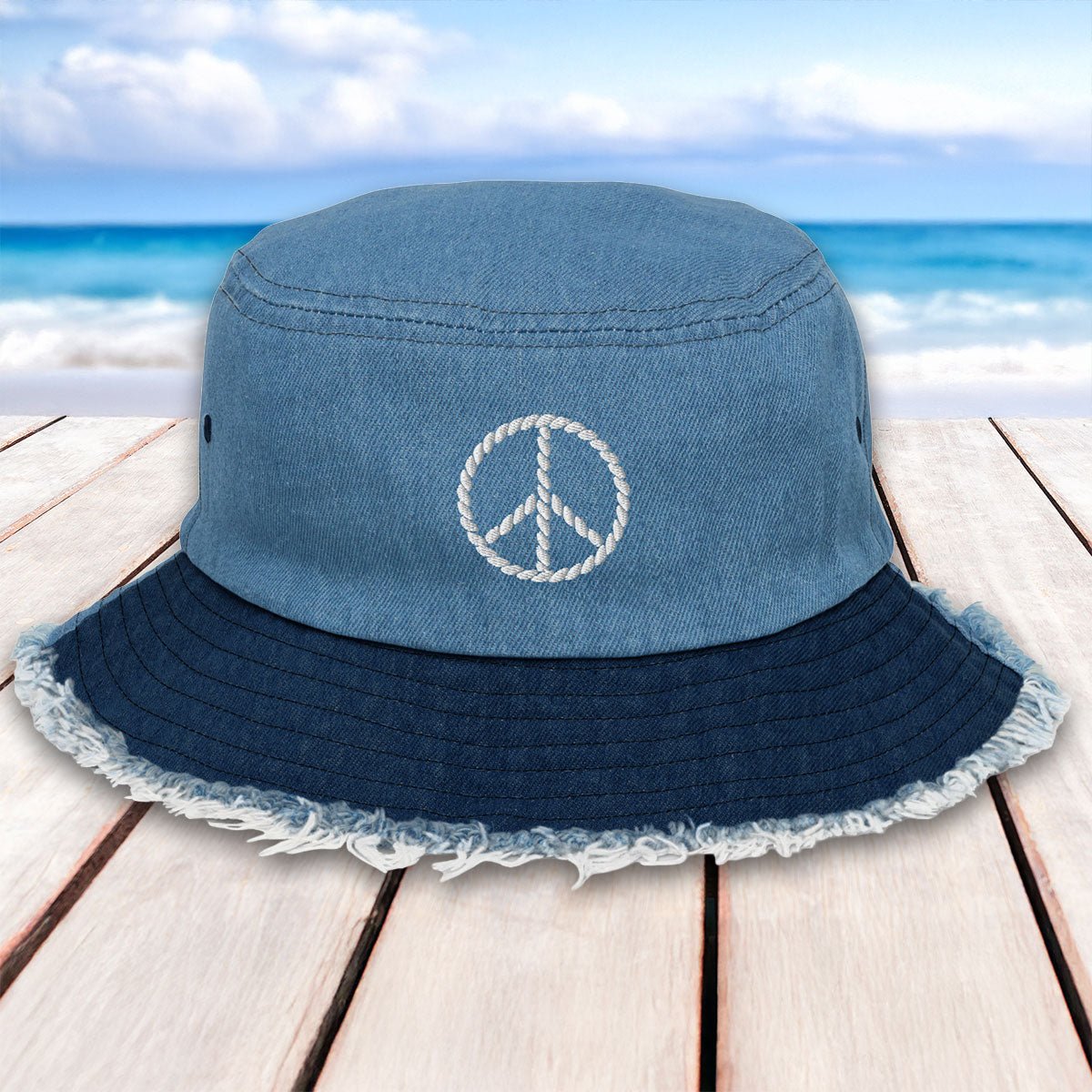Blue bucket hat with peace symbol on a wooden surface with beach background