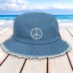 Blue bucket hat with peace symbol on a wooden surface with beach background