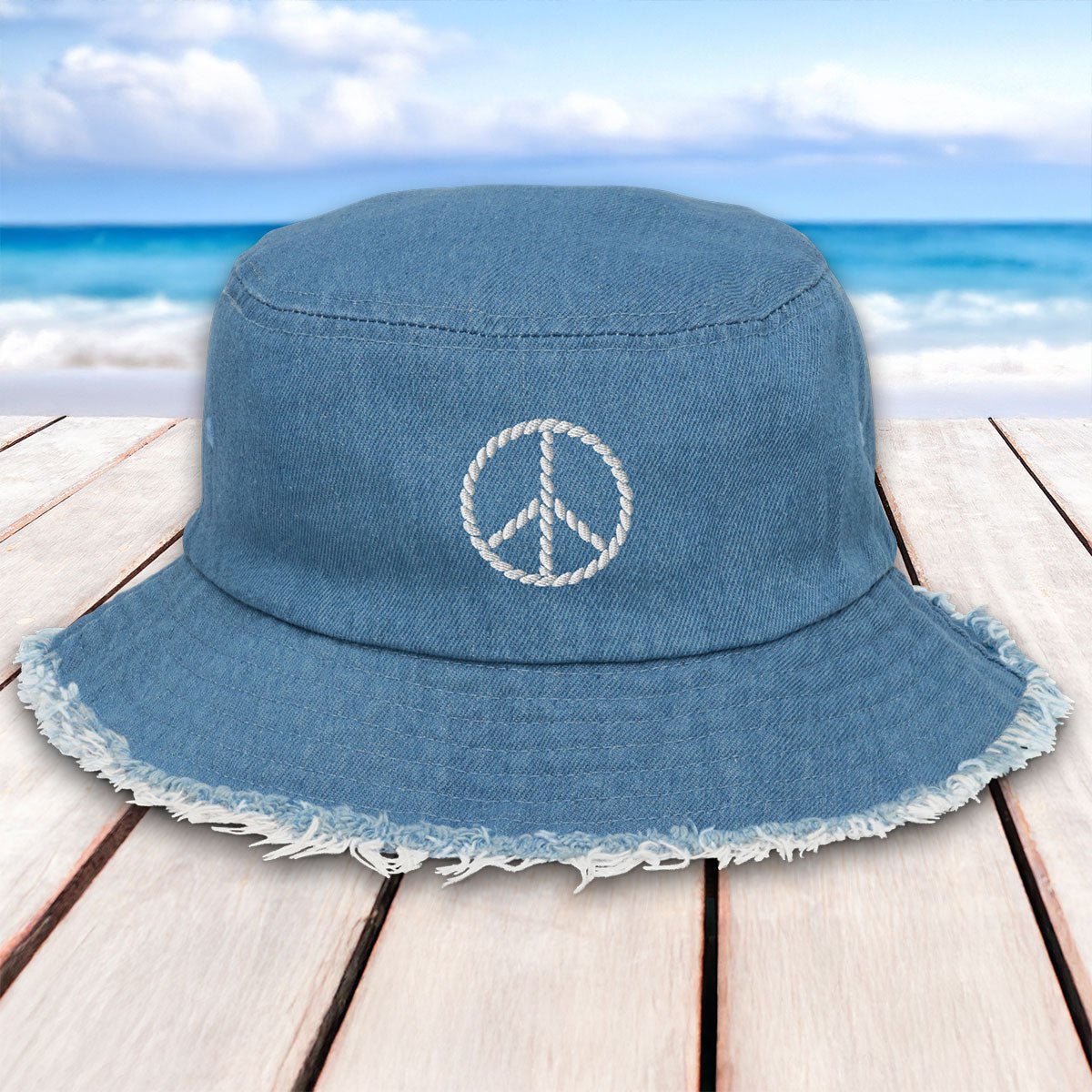 Blue bucket hat with peace symbol on a wooden surface with beach background