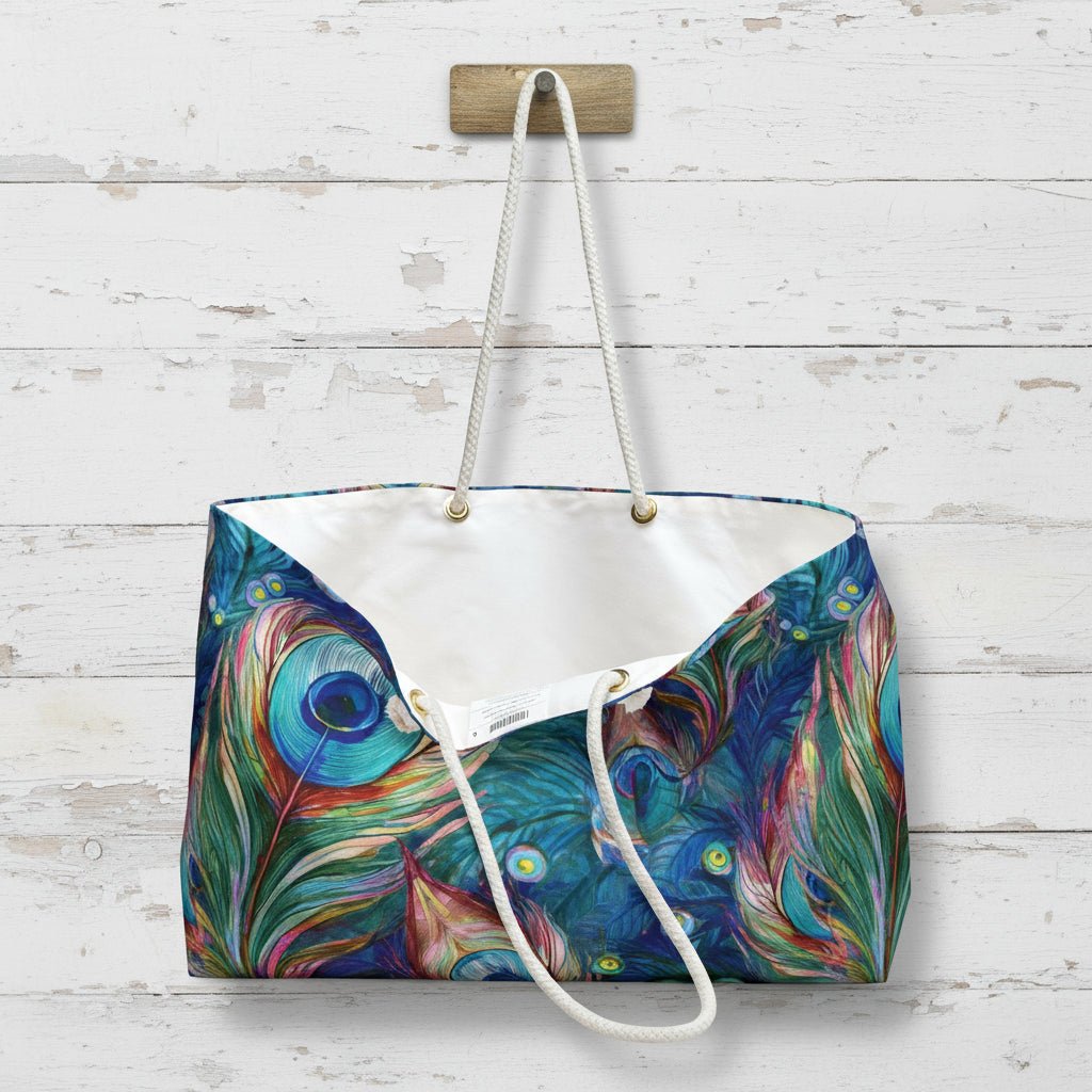 Tote bag with peacock feather pattern hanging on a wooden hook.