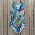 One-piece swimsuit with peacock feather design on a rustic wood background