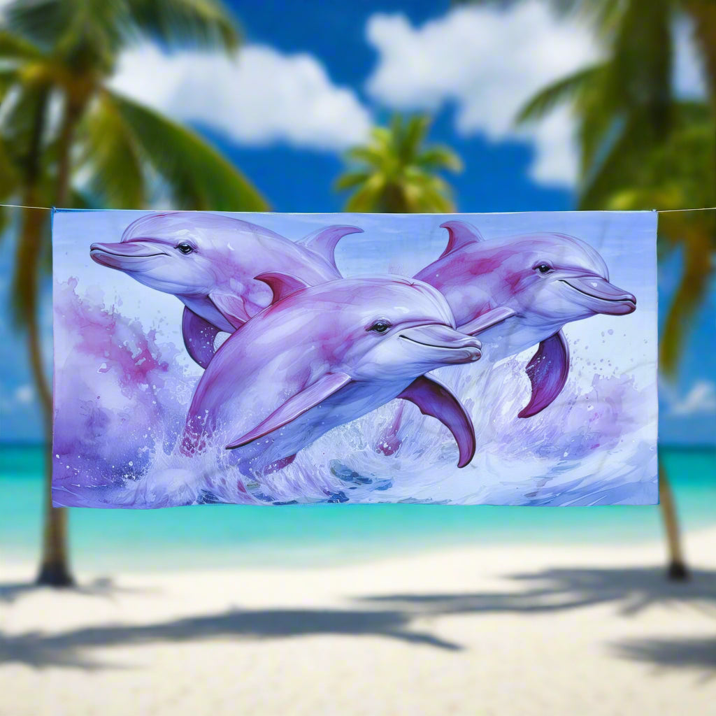 Pink and purple dolphins on a on a sweet beach towel hanging on a close line in a tropical paradise