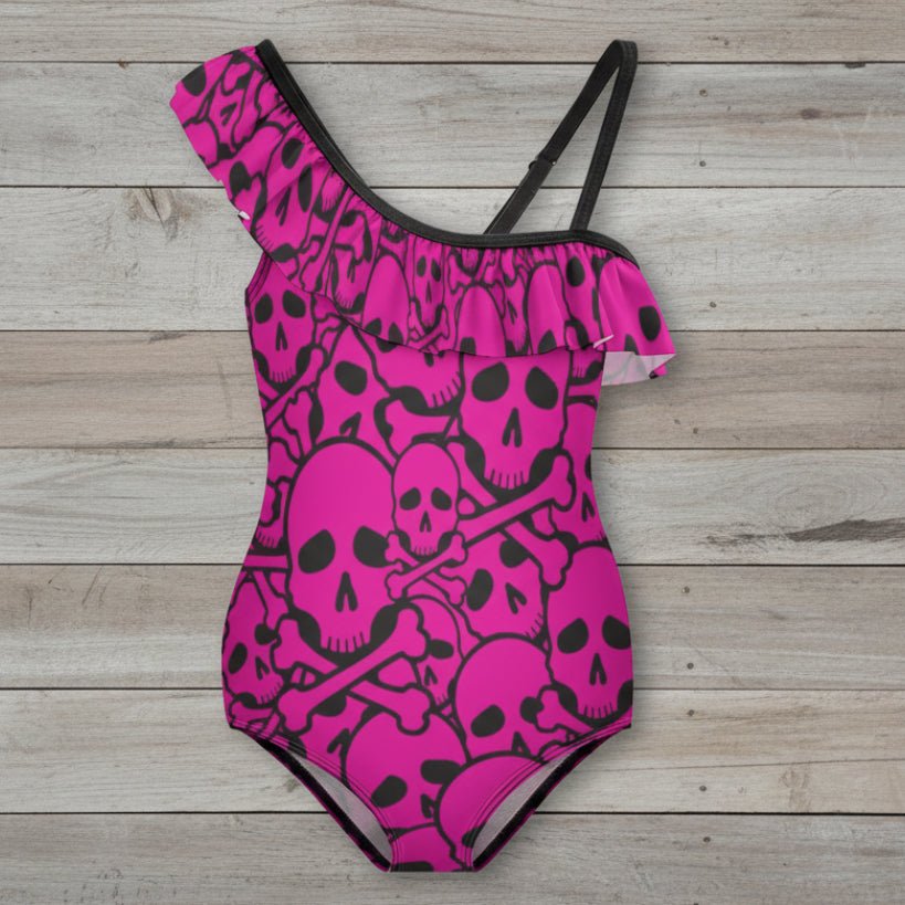 Pink Pirate swimsuit with black skull and crossbones pattern on nautical wood background