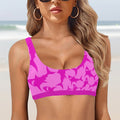 Woman wearing a pink camouflage sports bra against a faded beach background