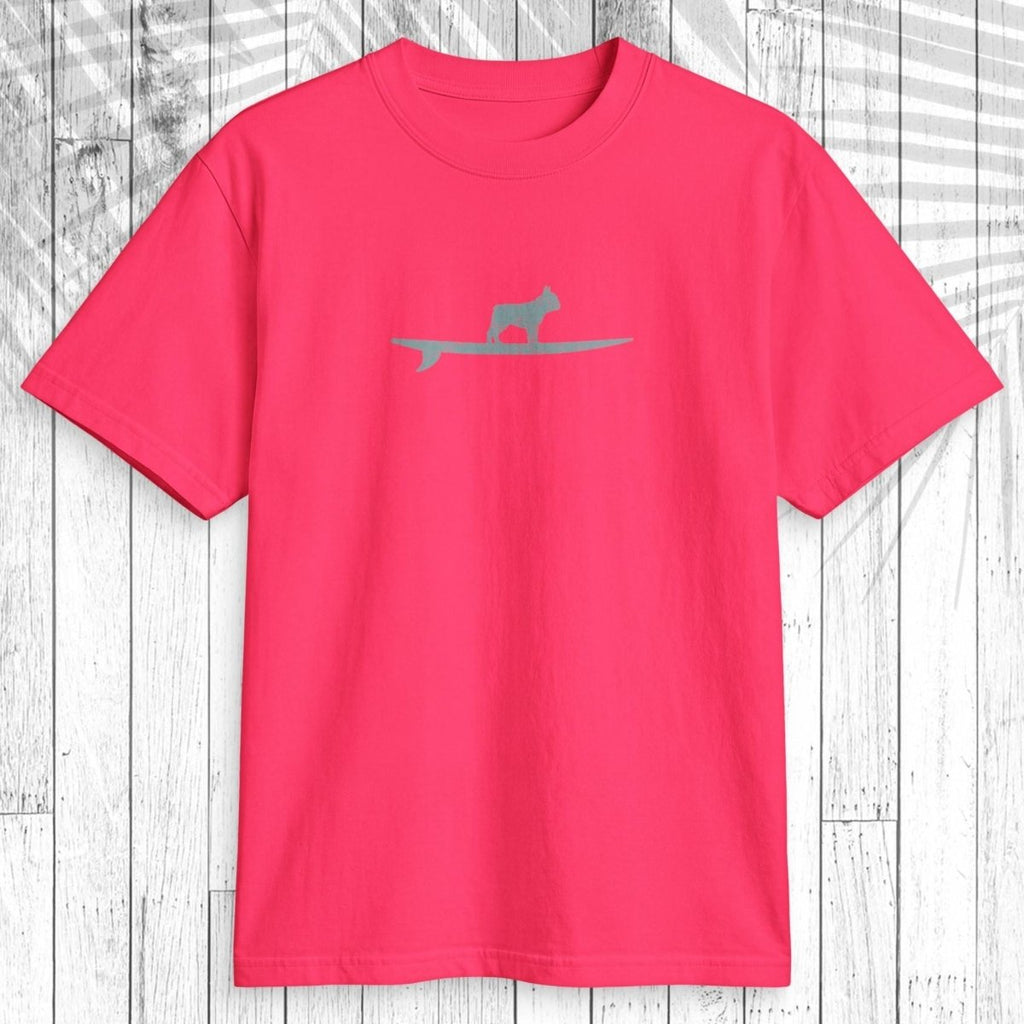 A bright pink short-sleeve t-shirt with a small gray silhouette of a cat on a surfboard across the chest, displayed flat against a white wood plank background.