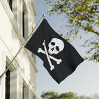Black flag with a skull and crossbones design on a building exterior.