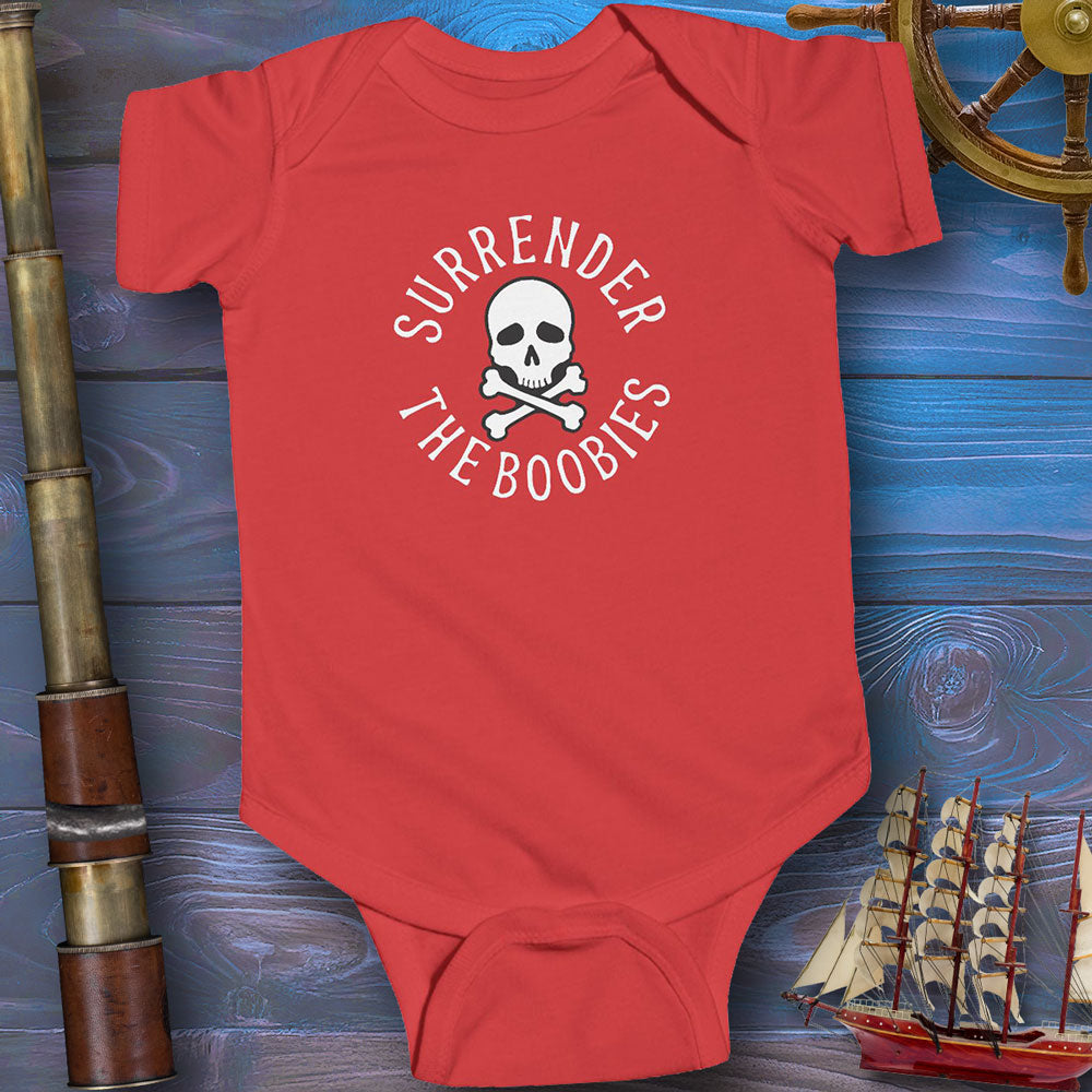 Red baby onesie with skull and crossbones design on a wooden background with ship and cannon.