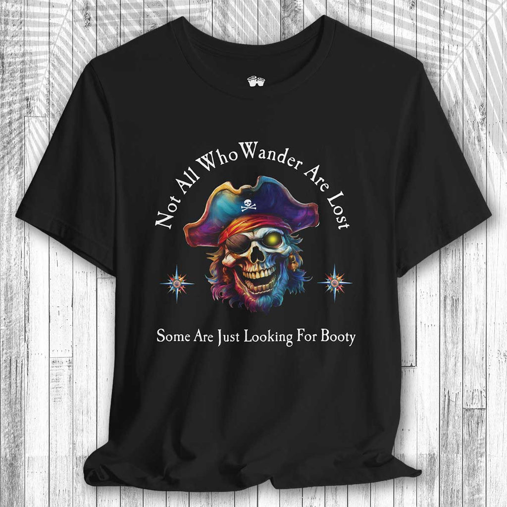 Black t-shirt with a colorful skull wearing a pirate hat and the text: "Not All Who Wander Are Lost – Some Are Just Looking For Booty" on a wooden surface