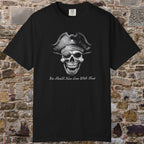 A black short-sleeve crewneck t-shirt featuring a grayscale graphic of a skull wearing a pirate hat with a skull-and-crossbones symbol, and the text 'You Should have gone with treat' below. The t-shirt is displayed flat against a rustic, textured stone brick wall background.