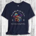 Navy blue t-shirt with a colorful skull wearing a pirate hat and the text: "Not All Who Wander Are Lost – Some Are Just Looking For Booty"  on a wooden surface