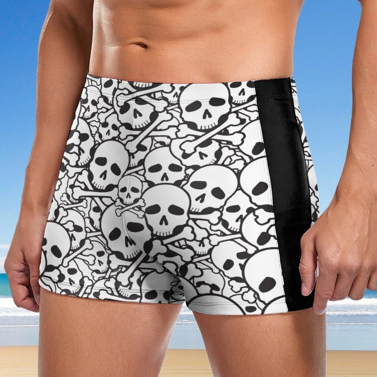 Person wearing black and white skull-patterned swim shorts with a beach background