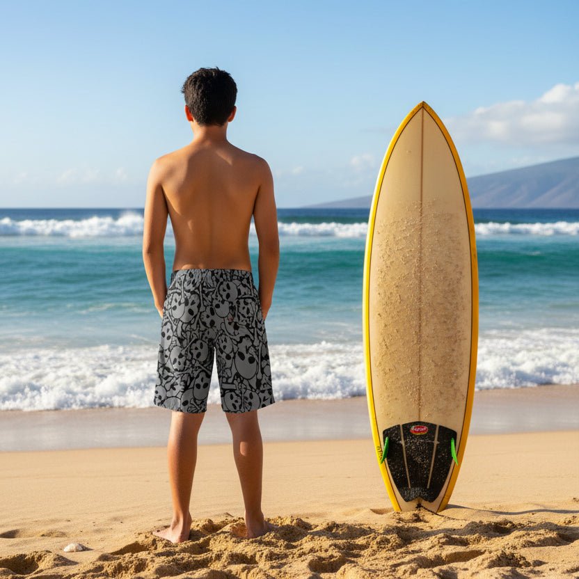 Young surfer dude wearing gray shorts with black skull pattern on Hawaii's North Shore