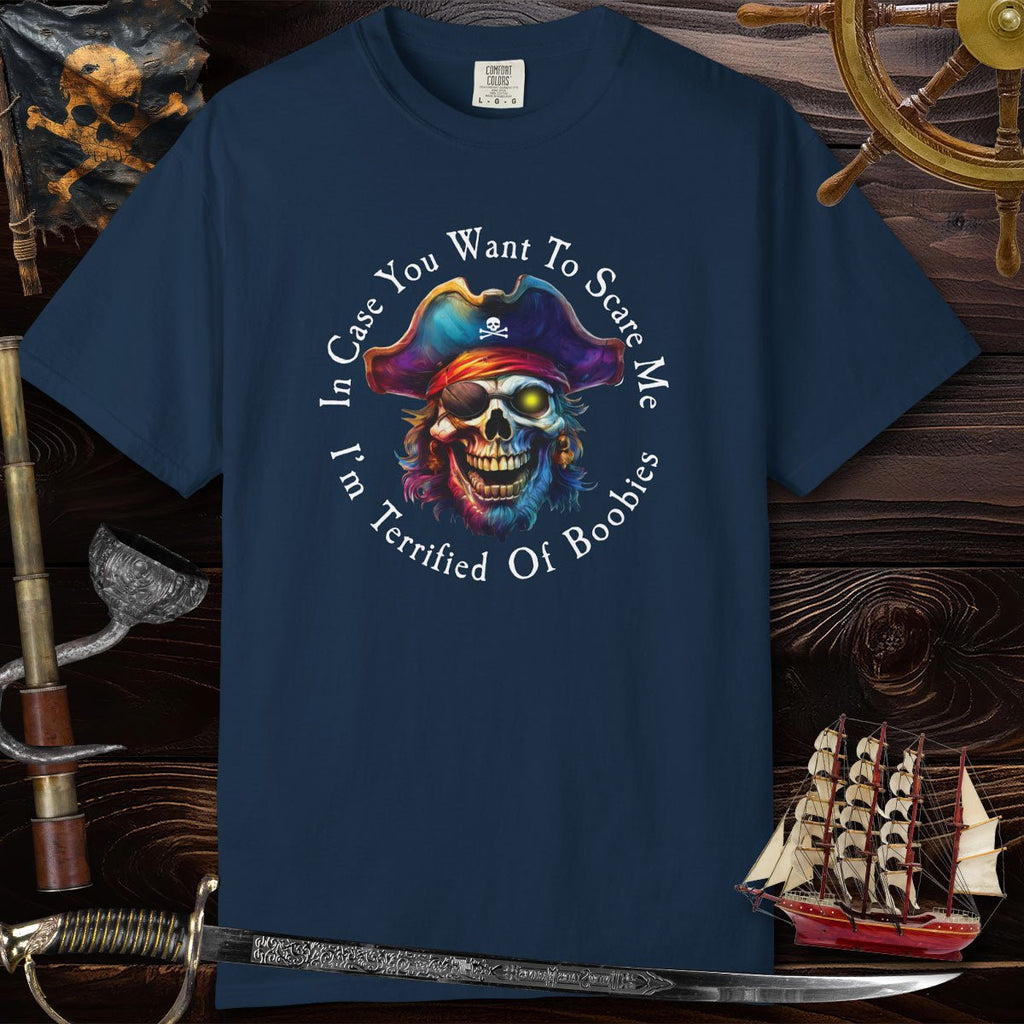 Navy blue t-shirt with a colorful pirate skull design and text on a wooden background with ship and sword.