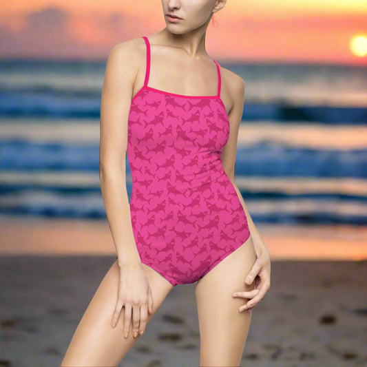 Woman in Hot Pink One Piece Bathing suit with sutel shark pattern is standing on the beach