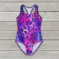 Woman wearing a purple and pink leopard print swimsuit on a rustic wood background