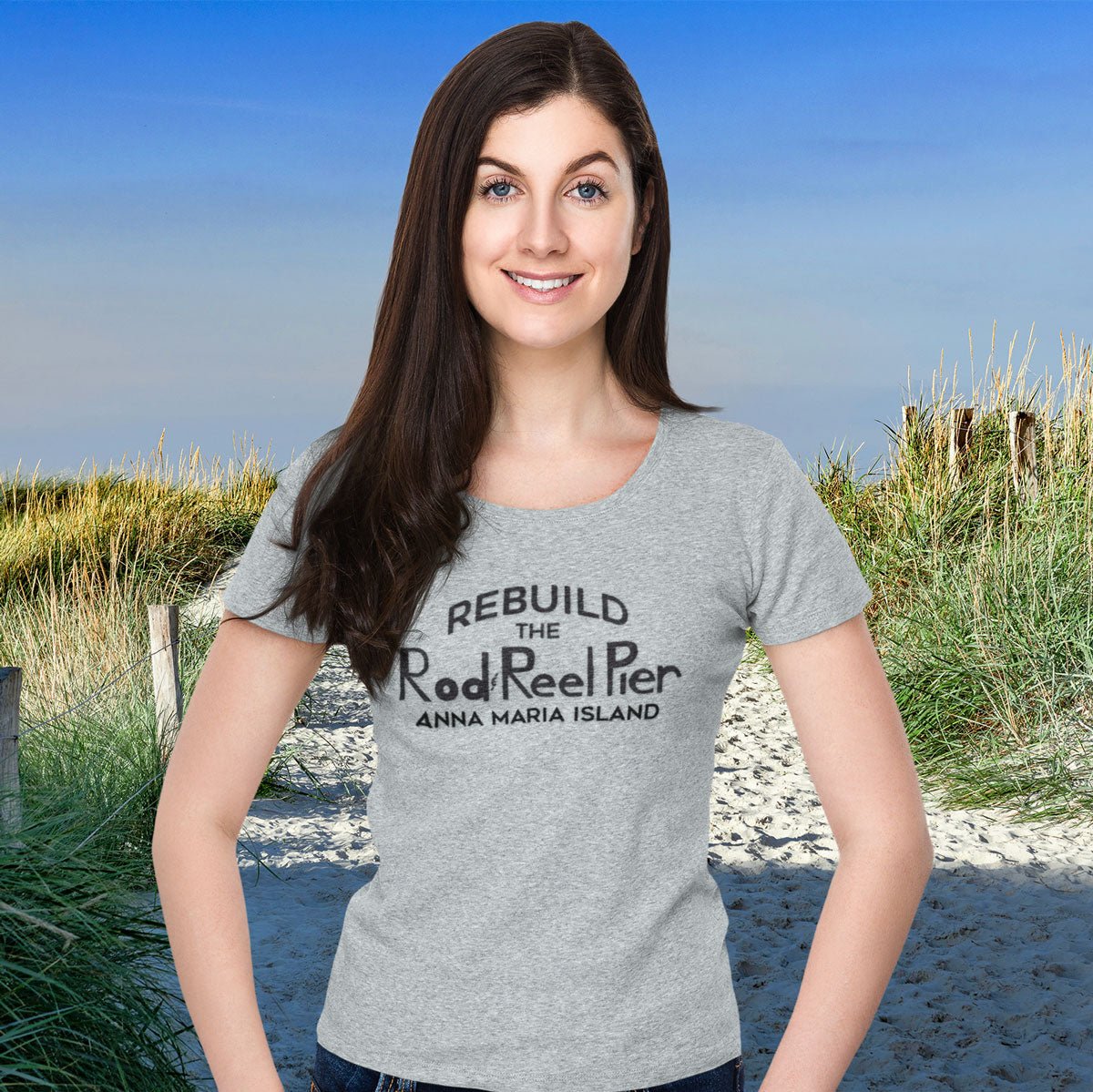 Woman wearing a gray t-shirt with text on it, standing on a beach.