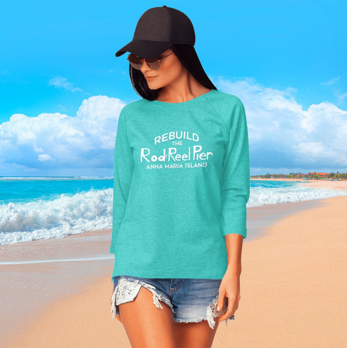 Woman wearing a teal shirt with text on a beach