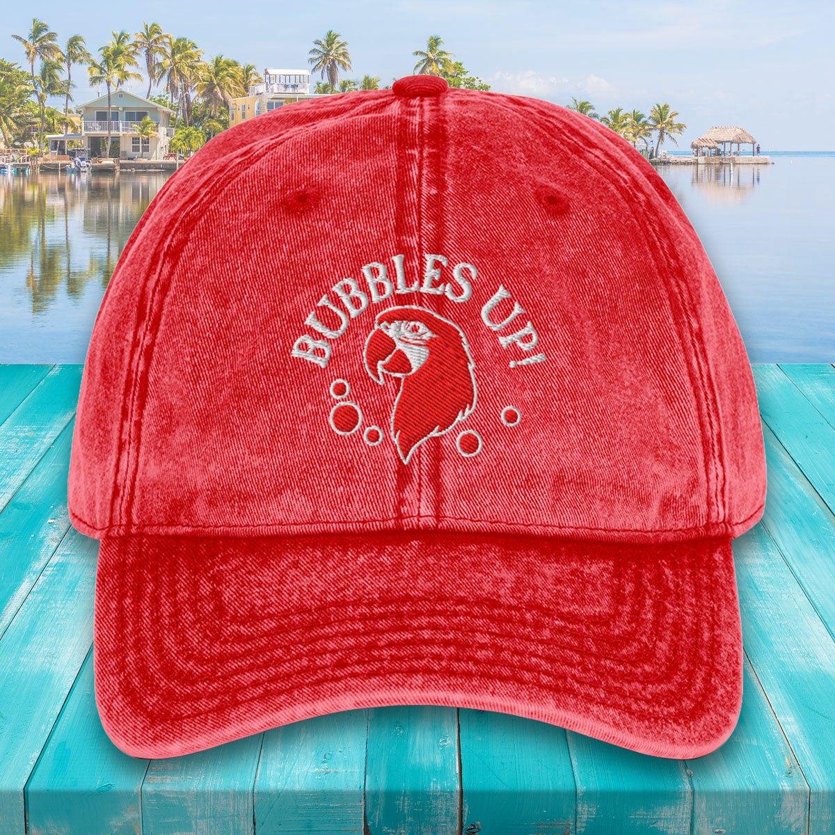 Red cap with 'Bubbles Up!' text and graphic on a teal surface with a pool and palm trees in the background