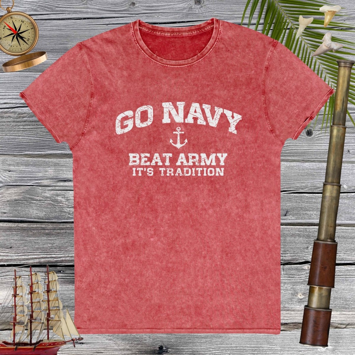 Red denim t-shirt with 'Go Navy, Beat Army, It's Tradition' text on a wooden background.