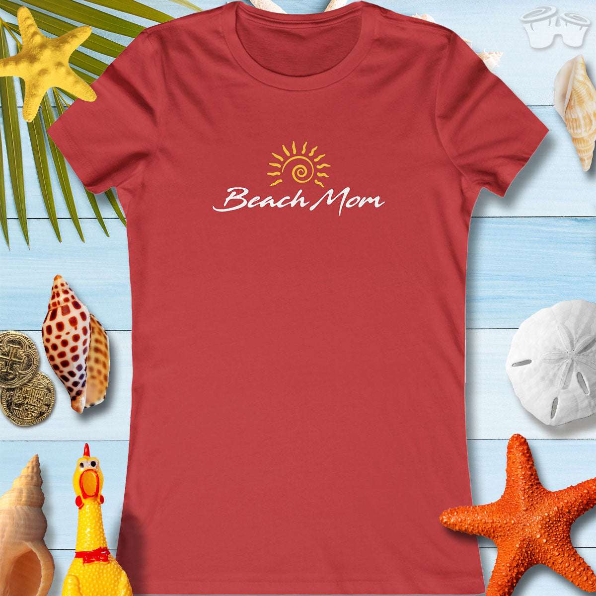 Women’s Beach Mom tee in red, perfect for summer fun and beach trips, surrounded by seashells and tropical decor.