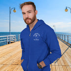 Man wearing a blue hoodie with a logo on a wooden pier by the ocean