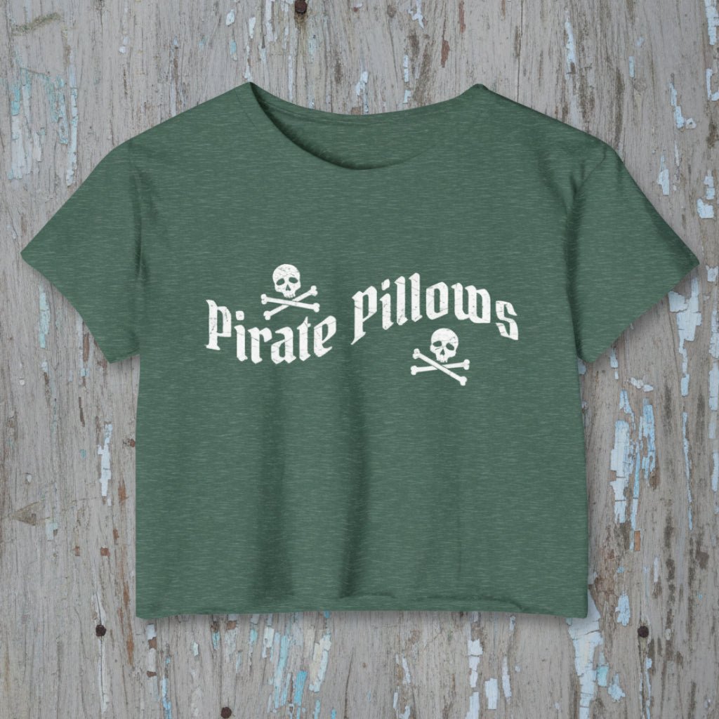 Green t-shirt with 'Pirate Pillows' text and skull design on a rustic wood background