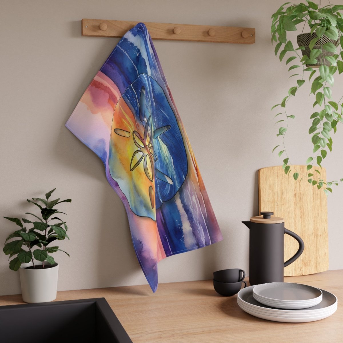 Colorful towel hanging on a wooden rack above a kitchen counter with plants and kitchenware.