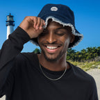 Man wearing a blue bucket hat with a lighthouse in the background