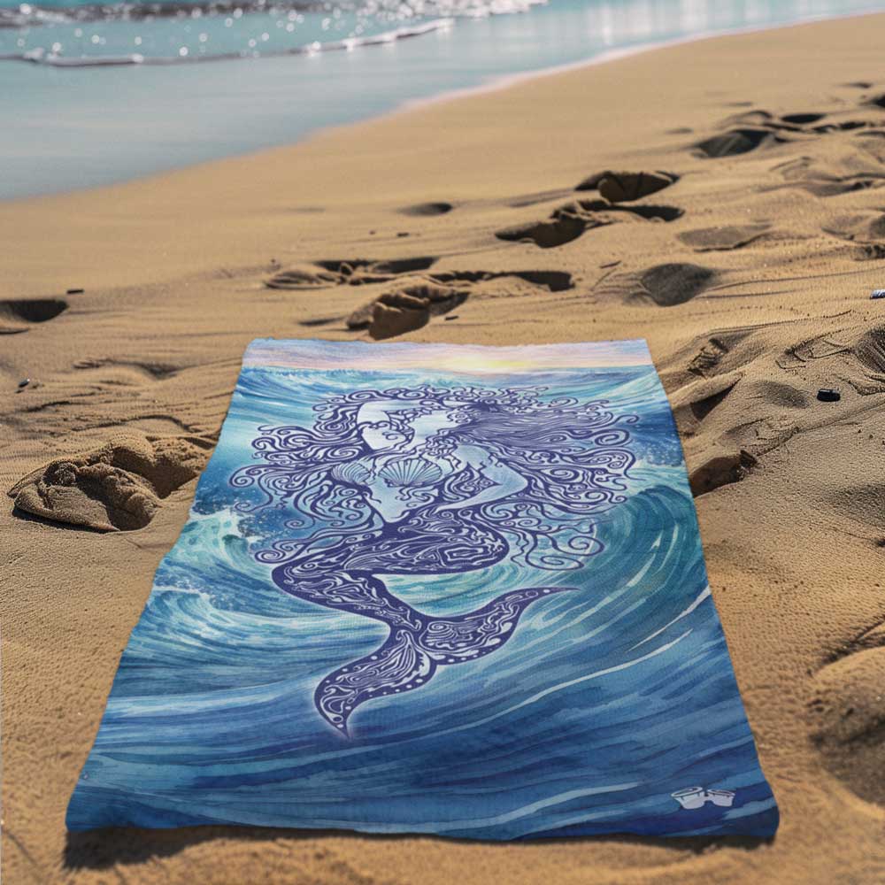 Zen Mermaid Beach Towel laying in the sand next to the waves