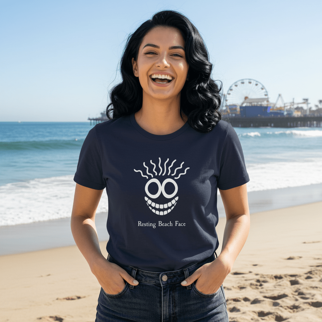A woman wearing a navy blue t-shirt with a white graphic of a funny face and the text 'Resting Beach Face', standing against a rustic wooden wall.
