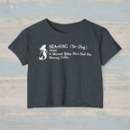 Black crop top with white mermaid graphic and text on a rustic woodbackground