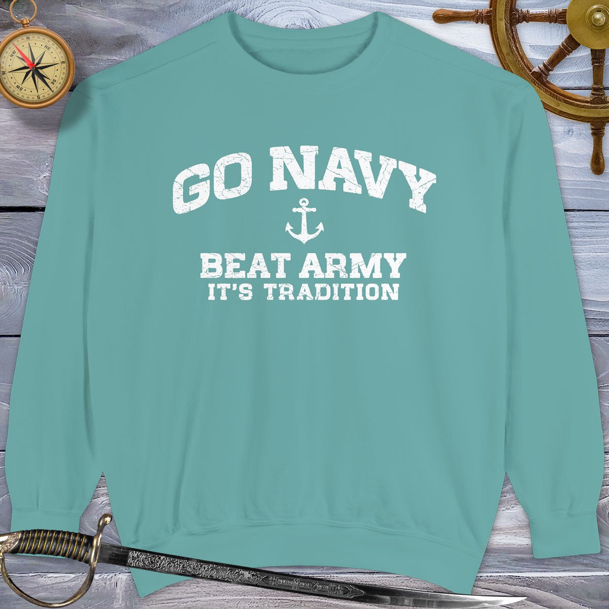 Teal Go Navy Sweatshirt with 'GO NAVY BEAT ARMY IT'S TRADITION' text on a wooden background.