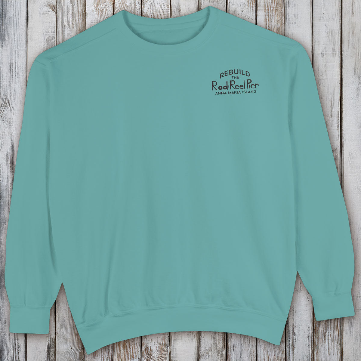 Teal sweatshirt with text on a wooden surface