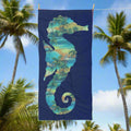 Navy Blue Beach Towel with outline of a seahorse around a vintage Hawaiian style pattern hanging on a line in a tropical paradise.