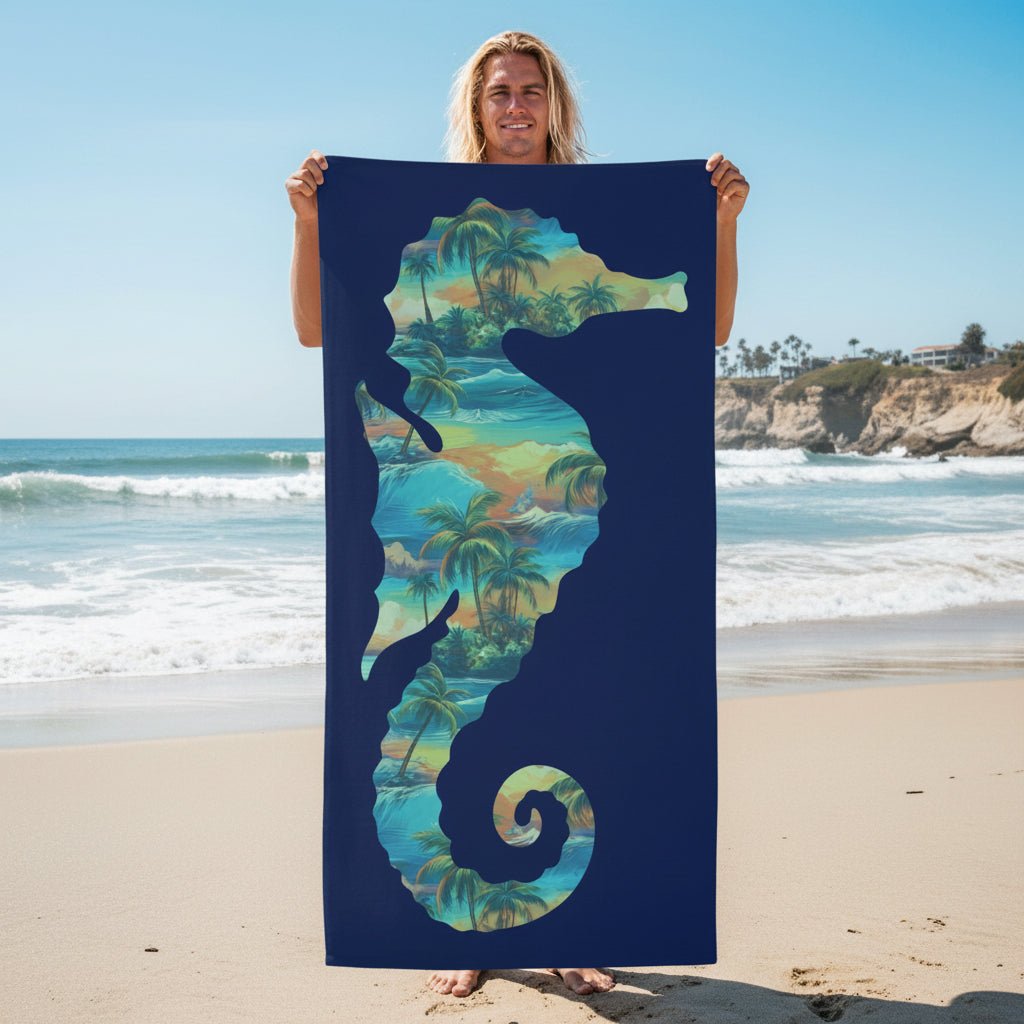 A rectangular beach towel with a dark navy blue background, featuring a large seahorse silhouette filled with a tropical palm tree and wave pattern in shades of teal, green, and yellow.