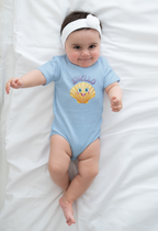 Baby wearing a blue onesie with a cartoon seashell character and Shello text, lying on a white blanket.