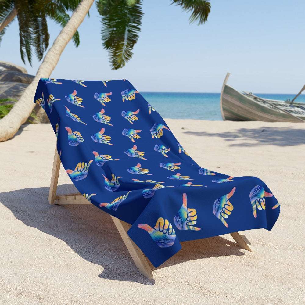Shaka wave beach towel hanging loose on a beach lounger with the sea and boat behind