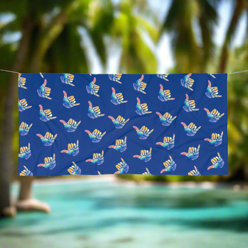 Blue Beach towel with shaka pattern hanging on a line on a tropical island