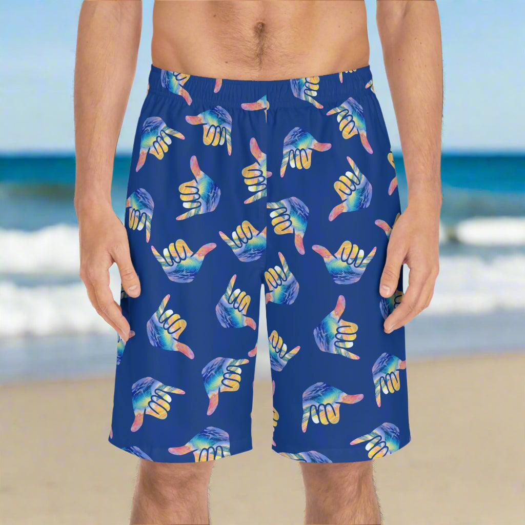 Surfer Standing on the beach wearing Bongo Beachwear Boardshorts with shaka sign pattern on royal blue shorts